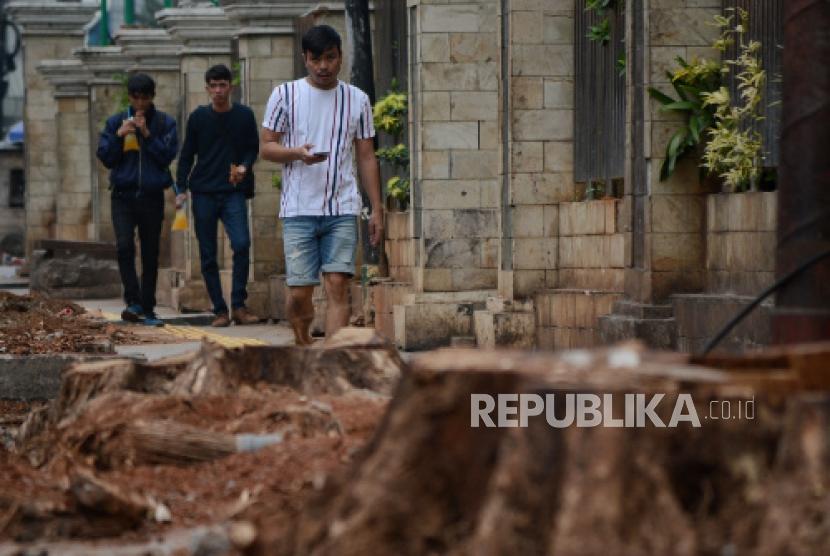 Pejalan kaki melintas di lahan bekas penebangan pohon di trotoar Cikini, Jalan Cikini Raya, Jakarta, Senin (4/11/2019).