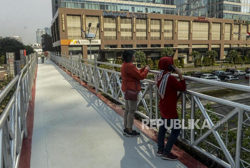 Pejalan kaki melihat pemandangan di jembatan penyeberangan orang (JPO) yang tidak beratap di Jalan Sudirman, Jakarta, Rabu (6/11).