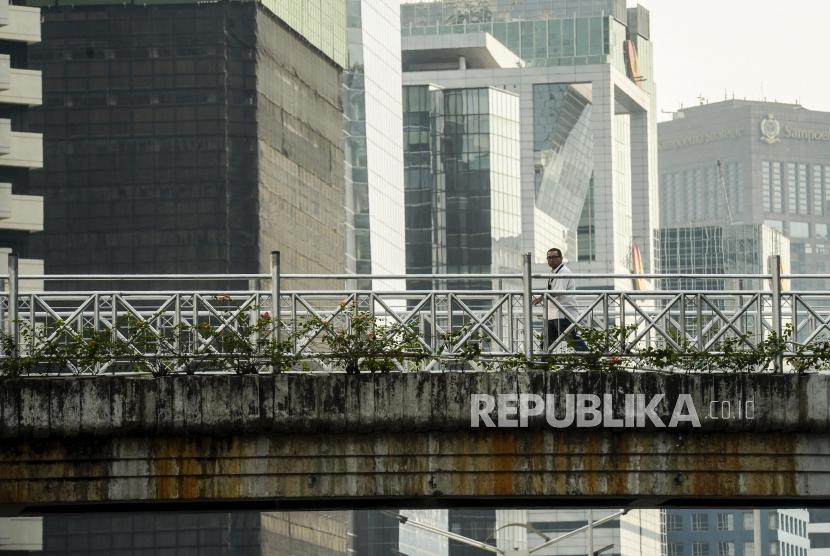 Pejalan kaki melintasi jembatan penyeberangan orang (JPO) yang tidak beratap di Jalan Sudirman, Jakarta, Rabu (6/11).