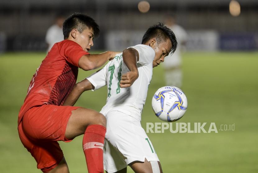 Pesepakbola Timnas Indonesia Mochammad Supriadi (kanan) berebut bola dengan pesepakbola Timnas Hongkong Chan Yu Tung pada pertandingan kualifikasi AFC U-19 di Stadion Madya, Jakarta, Jumat (8/11).