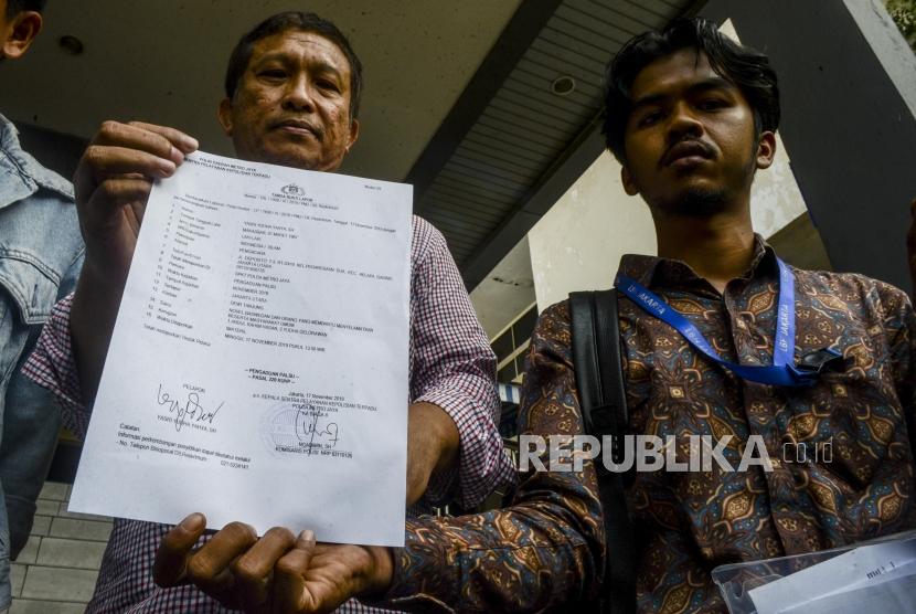 Tetangga yang juga saksi mata kasus penyiraman air keras yang menimpa penyidik senior KPK Novel Baswedan, Yasri Yudha Yahya (kiri) memperlihatkan kertas laporan polisi kepada wartawan usai melakukan pelaporan di Polda Metro Jaya, Jakarta, Ahad (17/11).