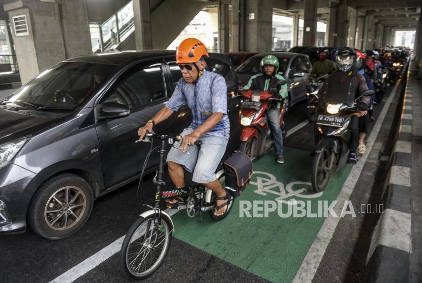 Seorang pesepeda melintasi jalur sepeda diantara para pengendara motor di Jalan RS Fatmawati Raya, Cilandak, Jakarta, Kamis (21/11).