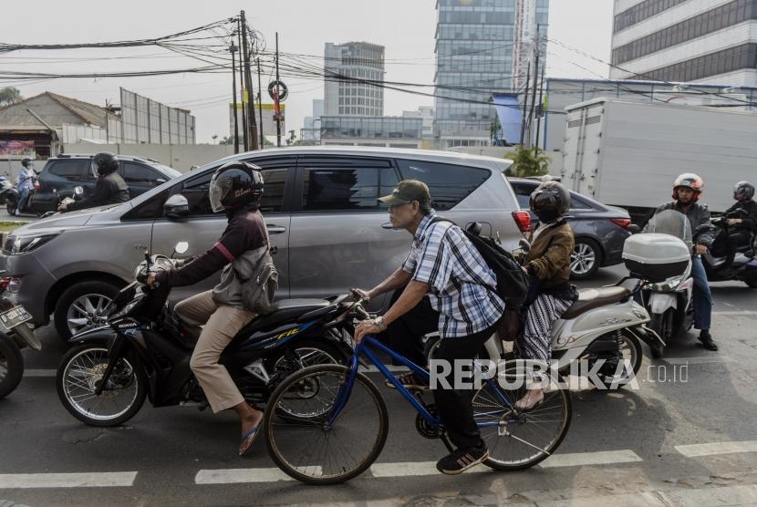 Seorang pesepeda melintasi jalur sepeda diantara para pengendara motor (ilustrasi).