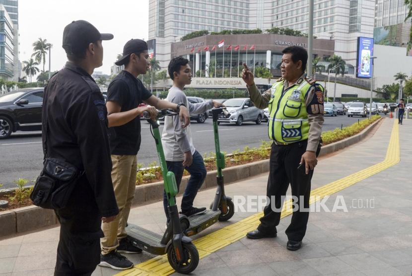 Anggota kepolisian memberi imbauan kepada pengguna skuter listrik yang melintas di Jalan MH Thamrin, Jakarta, Ahad. (Ilustrasi)