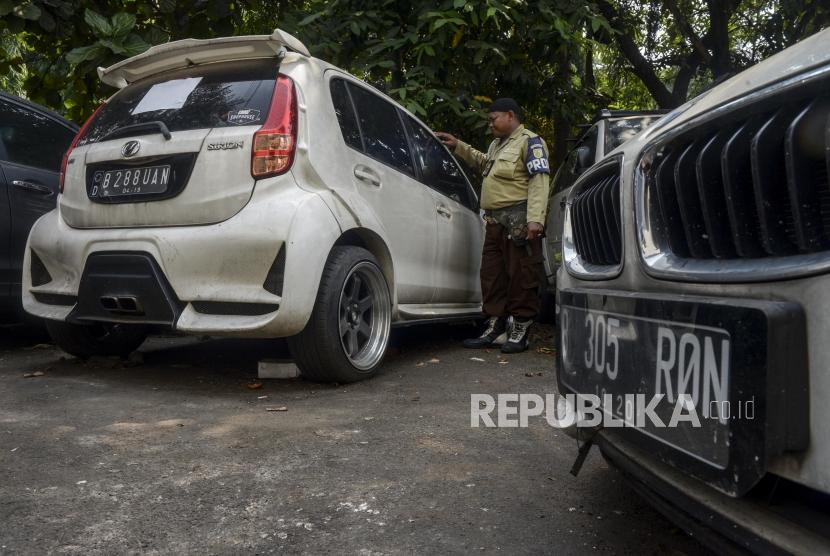 Petugas berada di dekat mobil sitaan aset First Travel di Kejaksaan Negeri Depok, Jawa Barat, beberapa waktu lalu..