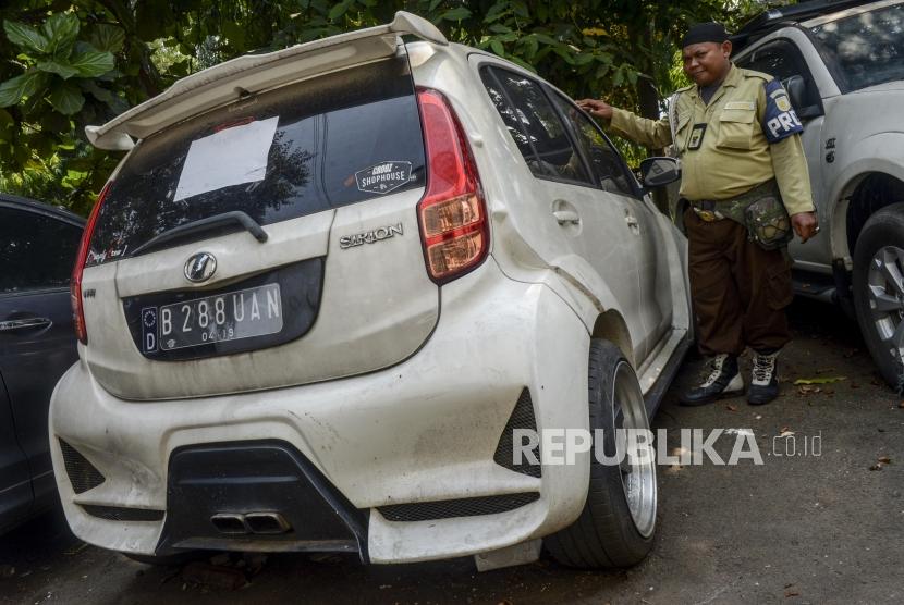 Petugas berada di dekat mobil sitaan aset First Travel di Kejaksaan Negeri Depok, Jawa Barat, Senin (25/11).