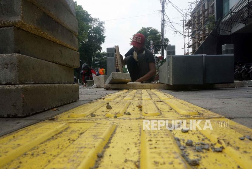 Pekerja memasang guiding block di trotoar Kemang, Jakarta, Rabu (27/11).