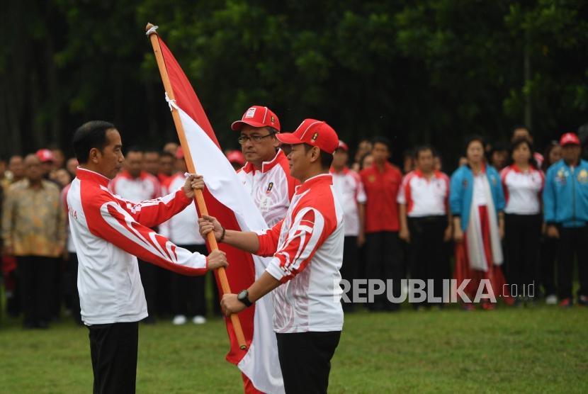 Presiden Joko Widodo (kiri) menyerahkan bendera kepada Ketua Komite Olimpiade Indonesia (KOI) Raja Sapta Oktohari (kanan) disaksikan Ketua Kontingen Indonesia Harry Warganegara (tengah) saat pelepasan atlet untuk SEA Games 2019 di Istana Bogor, Jawa Barat, Rabu (27/11/2019).