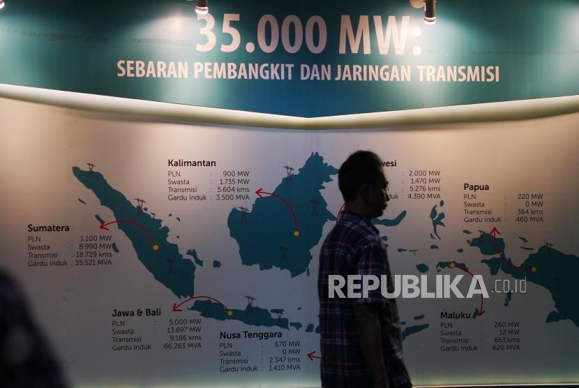 Seorang pengunjung melintasi backdrop target eletrtifikasi di Kantor Pusat PLN, Jakarta, Rabu (27/11).