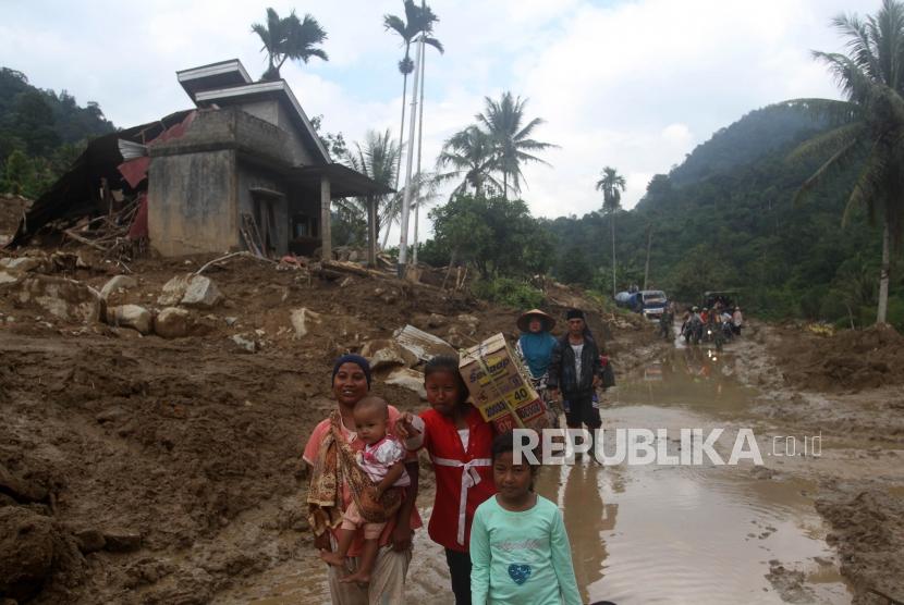 Sejumlah warga korban banjir bandang membawa bantuan di desa Sapan, Kecamatan Koto Parik Gadang di Ateh, Kabupaten Solok Selatan, Sumatera Barat, Kamis (28/11/2019).