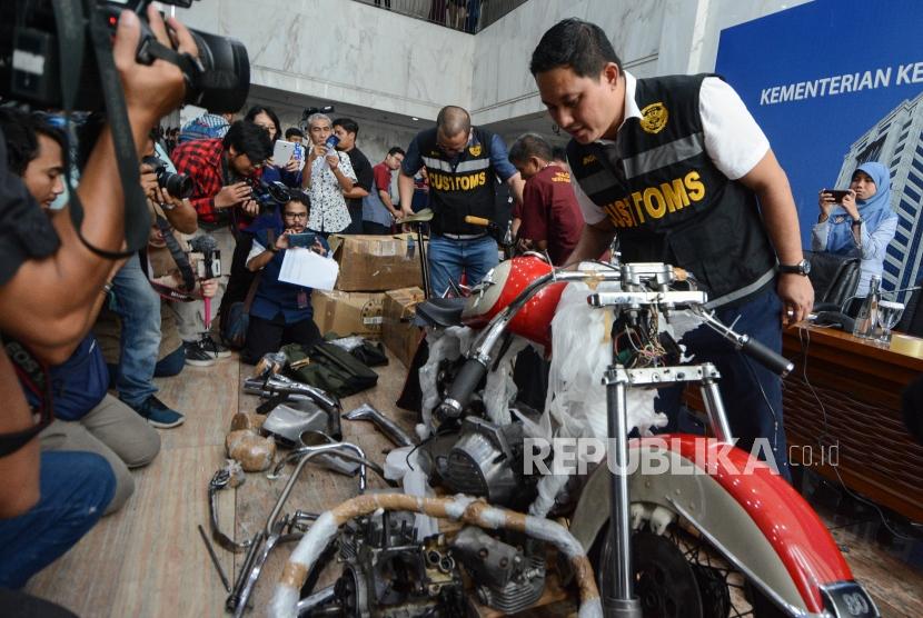 Petugas mengecek barang bukti temuan Motor harley Davidson saat konferensi pers di Gedung Kementerian Keuangan, Jakarta, Kamis (5/12).