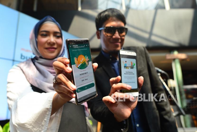 Artis Desta (kanan) dan Fitri Tropika (kiri) menunjukkan fitur pembukaan rekening online melalui Mandiri Syariah Mobile (MSM) di Jakarta, awal Januari 2020 lalu. PT Bank Syariah Mandiri (Mandiri Syariah) mengimbau nasabah mengoptimalkan metode pembayaran QRIS yanga ada dalam aplikasi MSM, di era new normal.