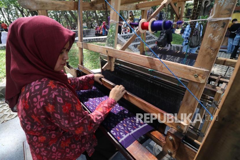 Perajin memperagakan cara membuat kain tenun ikat khas Kediri saat Dhoho Street Fashion di Taman Hutan Joyoboyo, Kota Kediri, Jawa Timur, Kamis (5/12/2019).