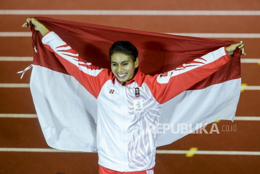Atlet lompat jauh Indonesia Maria Natalia Londa mengibarkan bendera merah putih usai pertandingan lompat jauh putri Sea Games 2019 di Stadion Atletik New Clark, Filipina, Ahad (8/12).