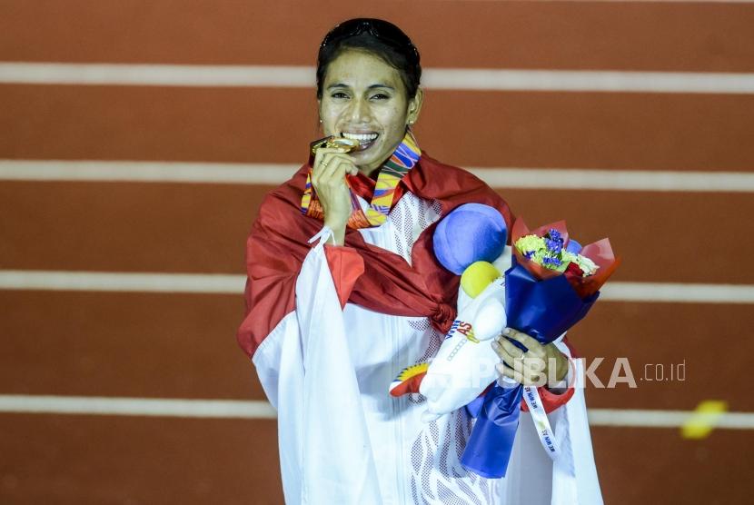 Atlet lompat jauh Indonesia Maria Natalia Londa menggigit medali emas usai pertandingan lompat jauh putri Sea Games 2019 di Stadion Atletik New Clark, Filipina, Ahad (8/12).