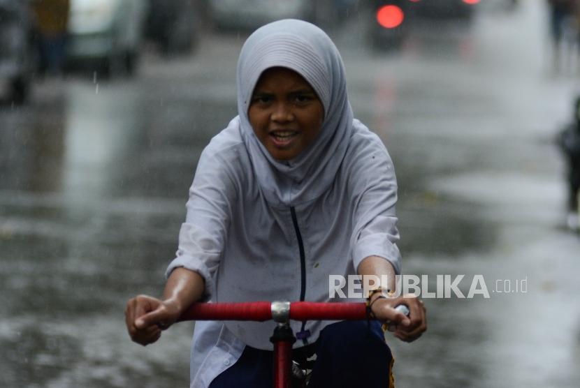 Anak bermain saat hujan lebat. BMKG Kelas I Juanda memprediksi hujan dan angin kencang akan melanda Jatim. Ilustrasi.