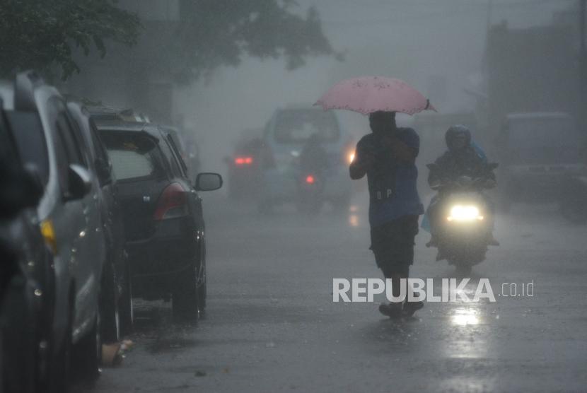 Sejumlah warga menggunakan payung menerobos hujan di kawasan Setiabudi, Jakarta, Selasa (17/12).