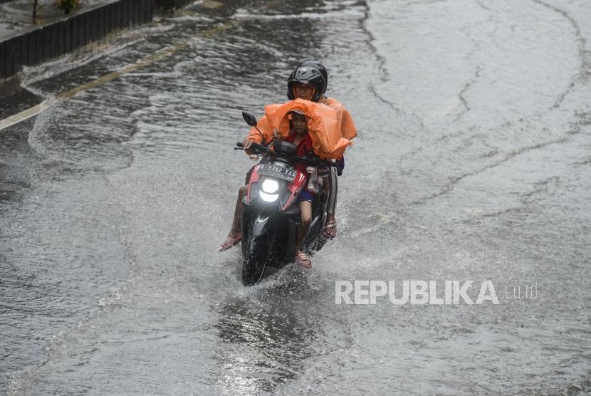 Pengendara motor menerobos genangan air. Foto (ILustrasi)