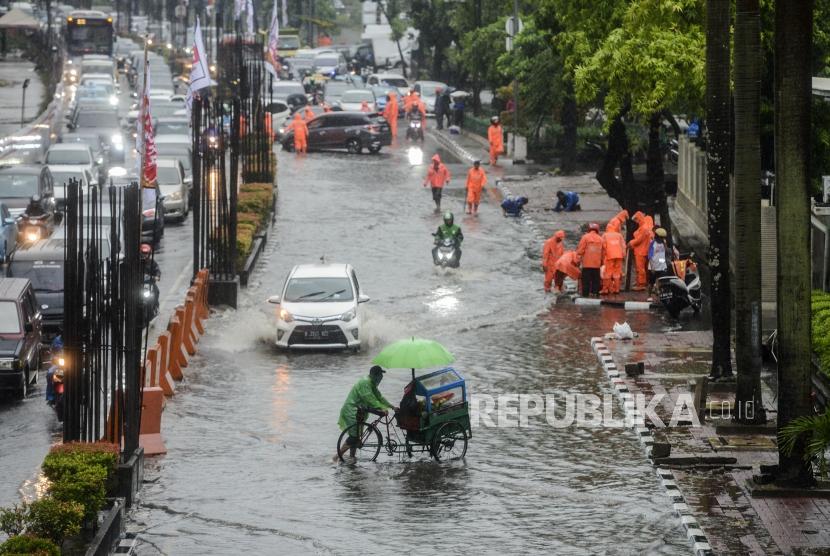 Jakarta sudah sejak zaman Kerajaan Purnawarman dilanda banjir. Foto pedagang melintasi jalanan di Jakarta yang tergenang air.