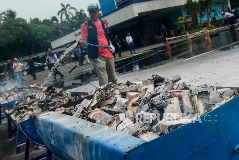 Sejumlah petugas menyiram barang bukti rokok ilegal yang telah dibakar di Kantor Bea Cukai, Rawamangun, Jakarta, Kamis, (19/12).