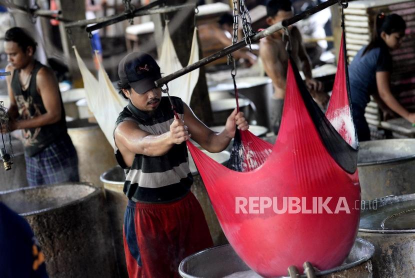 Pekerja menyelesaikan pembuatan tahu yang berbahan dasar kedelai di sebuah pabrik tahu. 