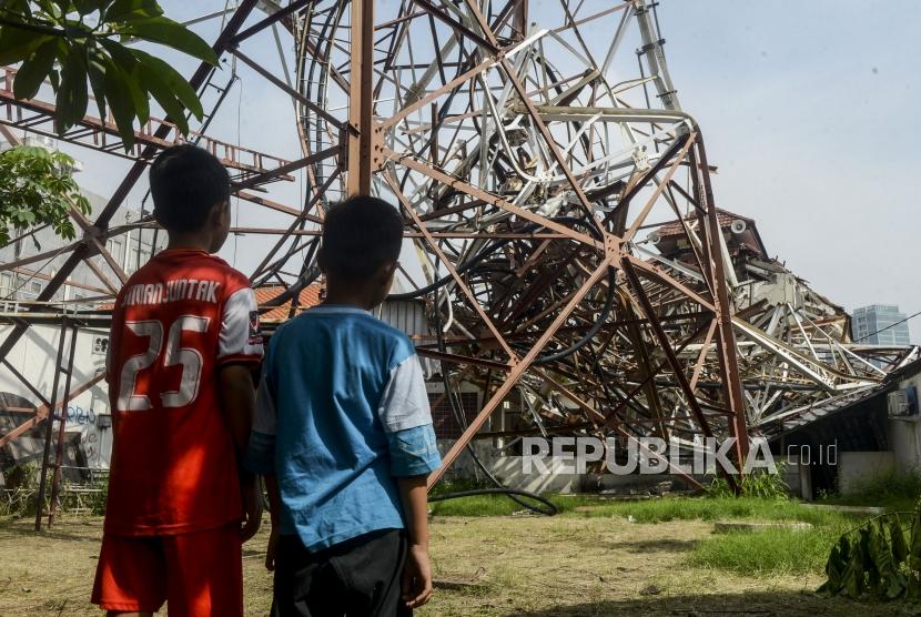Anak-anak melihat kondisi Menara Based Transmitter Station (BTS) yang roboh di kawasan Radio Dalam, Jakarta, Senin (23/12).