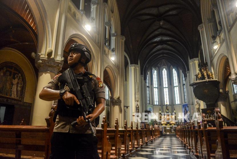 Gereja Katedral Gelar Tiga Misa Malam Natal. Foto: Petugas kepolisian melakukan penjagaan di Gereja Katedral, Jakarta, Senin (23/12).
