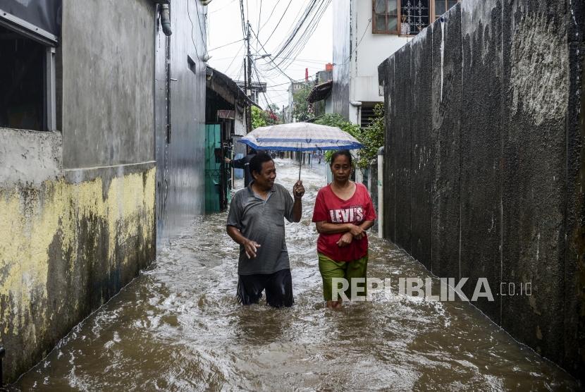 Sejumlah warga melintasi genangan banjir di kawasan Jatipadang, Pasar Minggu, Jakarta, Rabu (1/1).