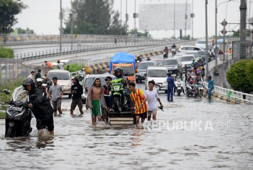 Warga di Kelurahan Aria Putra, Ciputat buka jasa menyeberangkan motor menembus banjir. Ilustrasi.