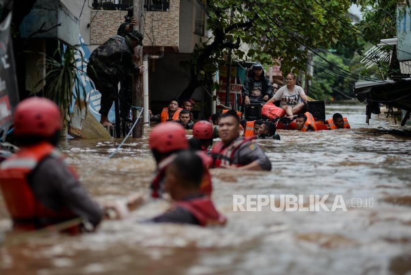 Petugas Kepolisian mengevakuasi korban banjir di Kampung Bayur, Cipinang Melayu, Jakarta Timur, Rabu (1/1).