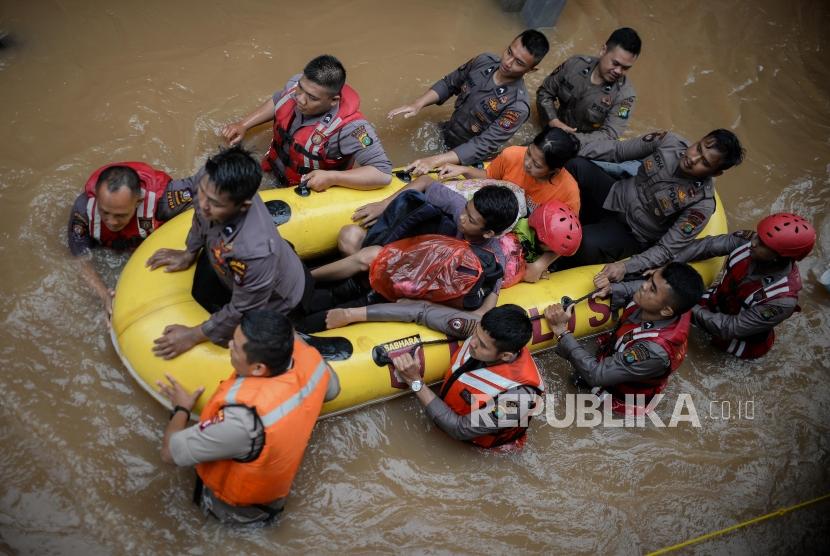 Petugas Kepolisian mengevakuasi korban banjir di Kampung Bayur, Cipinang Melayu, Jakarta Timur, Rabu (1/1). Sejumlah warga terserang ISPA, dermatitis, dan masalah lambung.