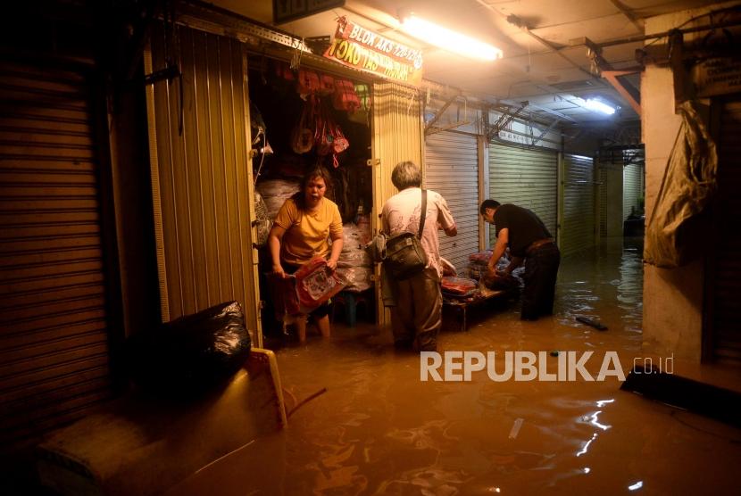 Sejumlah pedagang mengamankan barang dagangannya ketika banjir merendam lantai dasar Pasar Jatinegera, Jakarta, Kamis (2/1).