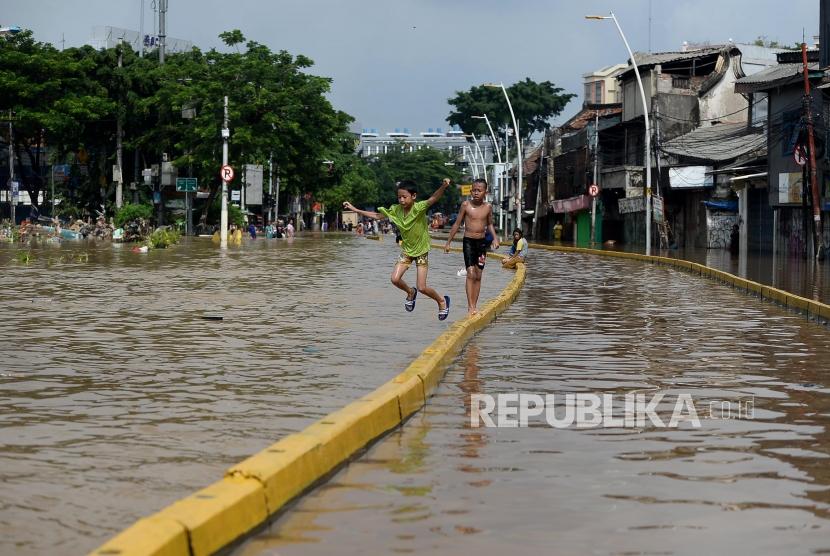 Anak-anak bermain saat banjir di Jalan Jatinegara Barat, Kampung Pulo, Jakarta, Kamis (2/1).