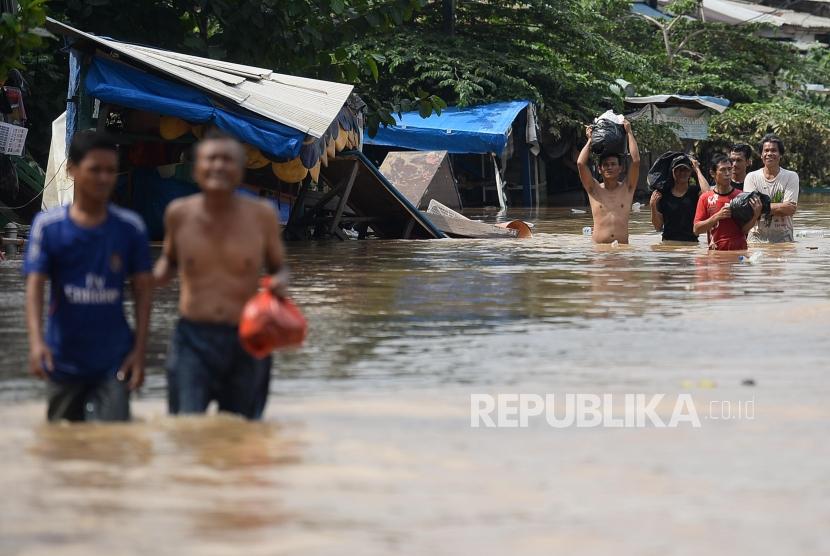 YBM BRI menyalurkan bantuan untuk warga korban banjir di Jakarta. Foto warga melintasi banjir di Jalan Jatinegara Barat, Kampung Pulo, Jakarta, (ilustrasi).