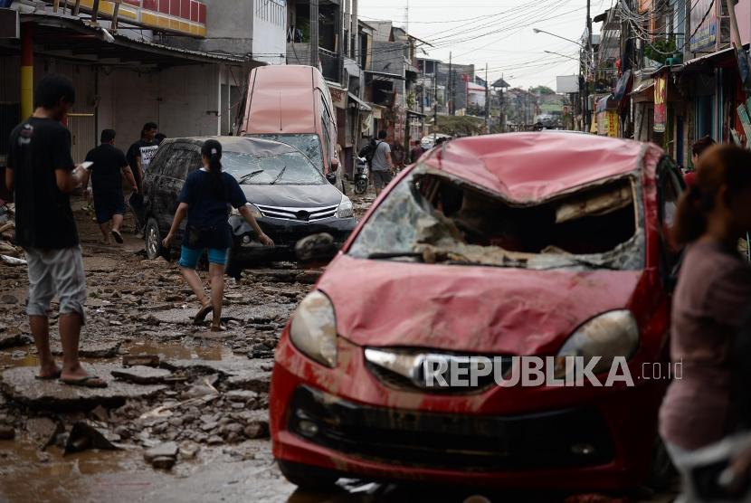Ridwan Kamil menilai penanganan banjir di Jawa Barat berbeda dengan di Jakarta. Foto: Sejumlah warga berjalan di dekat mobil yang rusak pascabanjir di Perumahan Pondok Gede Permai Bekasi, Jawa Barat, Kamis (2/1).