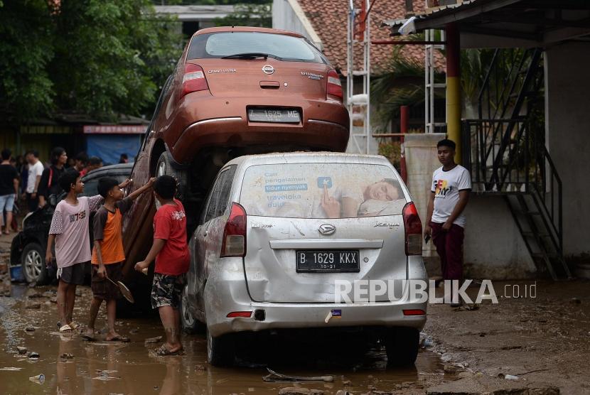 Anak-anak melihat mobil yang rusak pascabanjir di Perumahan Pondok Gede Permai Bekasi, Jawa Barat, Kamis (2/1).