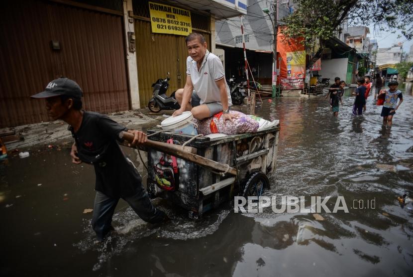 Sejumlah warga melawati genangan air banjir di Jalan Teluk Gong, Penjaringan, Jakarta Utara, Sabtu (4/11).