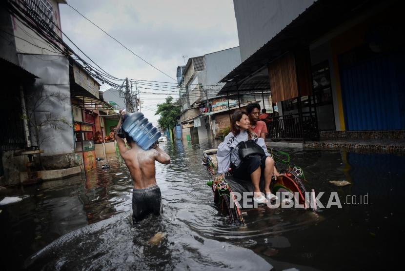Sejumlah warga melawati genangan air banjir di Jalan Teluk Gong, Penjaringan, Jakarta Utara, Sabtu (4/11).