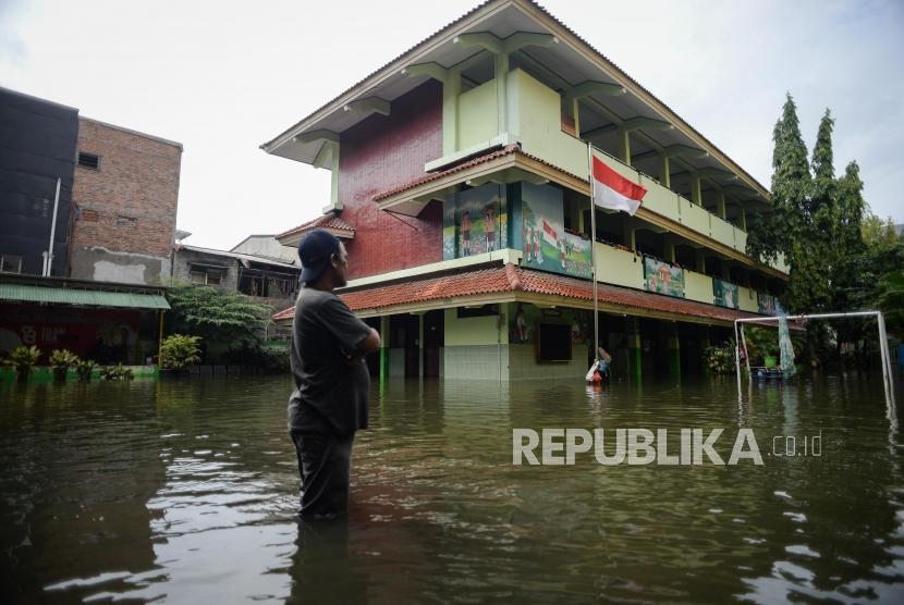 Petugas keamanan Sekolah Dasar Negeri (SDN) Pejagalan 05 pagi mengecek kondisi sekolah yang terendam banjir di Jalan Teluk Gong, Penjaringan, Jakarta Utara, Sabtu (4/1).