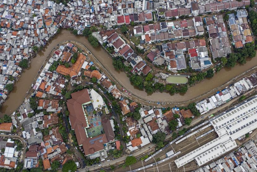 Foto udara suasana wilayah bantaran sungai Ciliwung yang belum dinormalisasi (atas) dan yang sudah dinormalisasi (bawah) di kawasan Bukit Duri, Jakarta, Minggu (5/1/2020).
