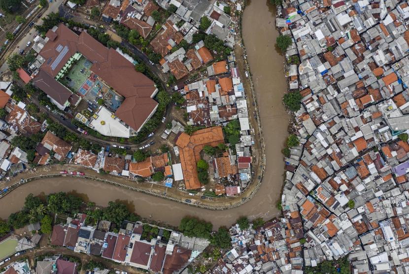 Foto udara suasana wilayah bantaran sungai Ciliwung yang belum dinormalisasi (bawah) dan yang sudah dinormalisasi (kiri) di kawasan Bukit Duri, Jakarta, Minggu (5/1/2020).