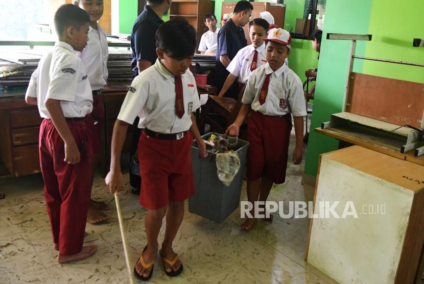 Siswa Sekolah Dasar Negeri Kapuk Muara 01 bergotong royong membersihkan sisa lumpur pasca banjir di Jakarta, Senin (6/1/2019).