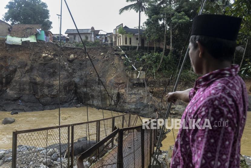 Seorang warga memperlihatkan jembatan yang putus akibat banjir bandang dan longsor di Desa Sukaraksa, Cigudeg, Bogor, Jawa Barat.