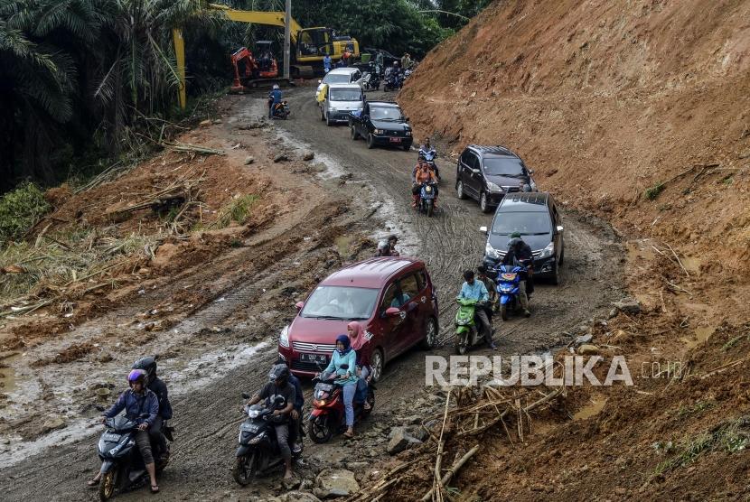 Sejumlah kendaraan melintasi jalanan yang telah dibuka akibat longsor di Desa Harkatjaya, Sukajaya, Bogor, Jawa Barat, Senin (6/1).