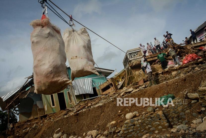 Warga menerima bantuan menggunakan bantuan keretan baja di Kampung Muara, Desa Banjarsari, Kecamatan Lebak Gedong, Banten, Senin (13/1).