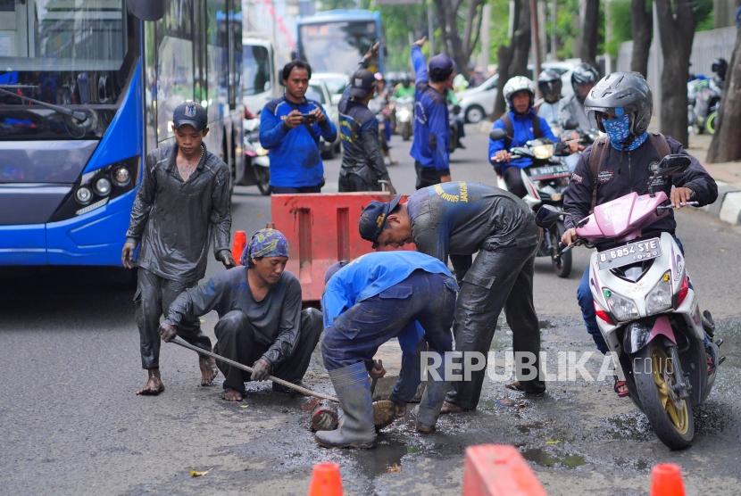 Petugas menutup lubang drainase (ilustrasi) 