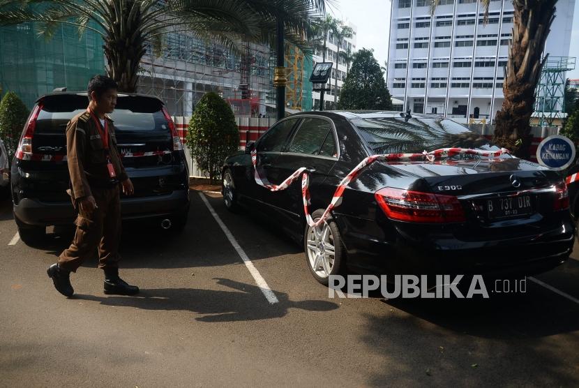 Petugas Kejaksaan Agung RI melintas didekat kendaraan barang bukti sitaan kasus korupsi Asuransi Jiwasraya yang terpakir di Gedung Tindak Pidana Khusus, Kejaksaan Agung RI, Jakarta, Jumat (17/1).