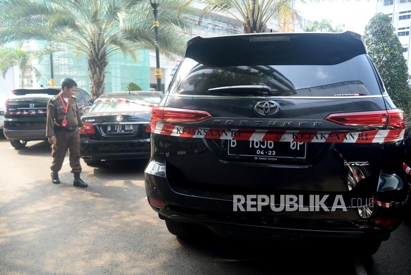 Petugas Kejaksaan Agung RI melintas didekat kendaraan barang bukti sitaan kasus korupsi Asuransi Jiwasraya yang terpakir di Gedung Tindak Pidana Khusus, Kejaksaan Agung RI, Jakarta, Jumat (17/1).