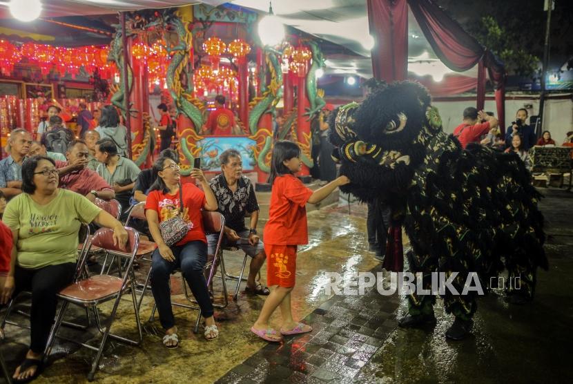 Seorang anak keturunan Tionghoa memberikan angpao kepada barongsai usai melaksanakan sembahyang di Vihara Amurva Bhumi, Karet, Jakarta, Jumat (24/1).