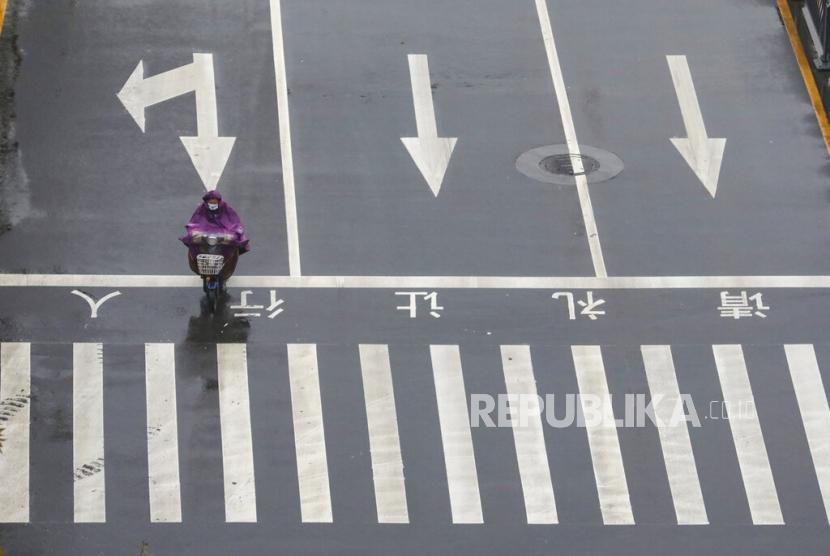 Seorang pengendara sepeda motor melintasi jalanan Kota Wuhan yang kosong, Sabtu (25/1). Pemerintah China melarang warganya bepergian selain mengisolasi kota.